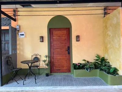 a front door of a house with a table and chairs at The Snug Airportel - Phuket Airport in Nai Yang Beach