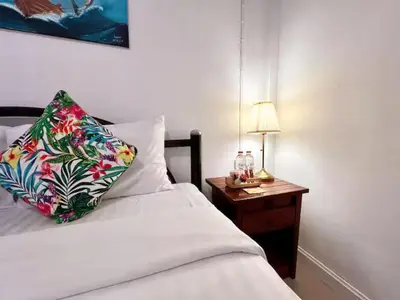 a bed with a pillow and a table with a lamp at The Snug Airportel - Phuket Airport in Nai Yang Beach