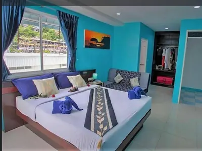 a bedroom with two beds and a blue wall at PATONG BLUE HOTEL in Patong Beach
