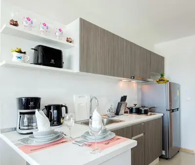 a kitchen with a counter with glasses and a refrigerator at KATA BEACH OZONE Superb Fully Equipped studio kitchen washing machine aircon in Kata Beach