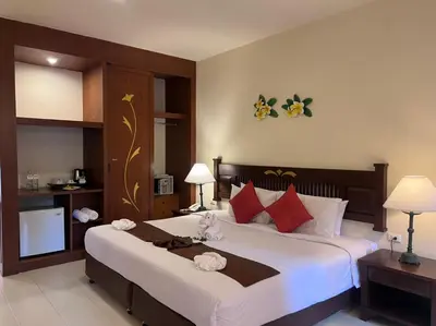 a bedroom with a large bed with white sheets and red pillows at Phuket Leelavadee Hua Ting Resort in Patong Beach