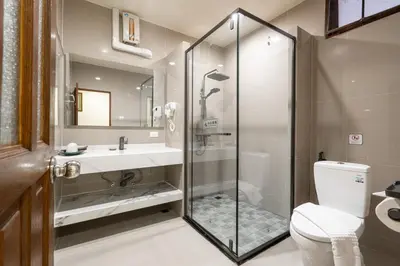 a bathroom with a shower and a sink and a toilet at Phuket Leelavadee Hua Ting Resort in Patong Beach