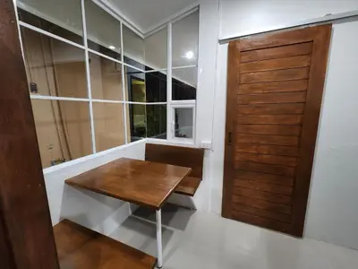 a room with a wooden table and a wooden door at Hommory Residence - West Chalong in Ban Klang