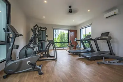a gym with several treadmills and exercise bikes at Title V by Villacarte in Rawai Beach