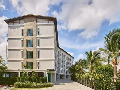 a white building with palm trees in front of it at Title V by Villacarte in Rawai Beach
