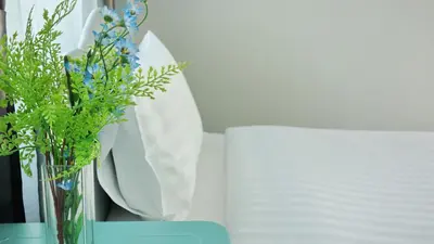 a vase with blue flowers sitting on a table at Kata Bai D - SHA Certificate Hotel in Kata Beach