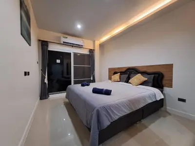 a bedroom with a bed with blue pillows on it at Triple J Hometel in Bang Tao Beach