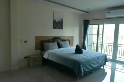 a bedroom with a bed with a cat sitting on it at Triple J Hometel in Bang Tao Beach