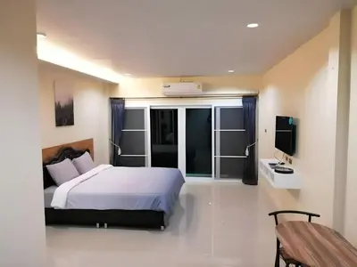 a bedroom with a white bed and a television at Triple J Hometel in Bang Tao Beach
