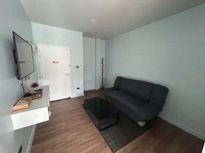a living room with a couch and a television at Triple J Hometel in Bang Tao Beach