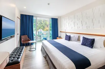 a hotel room with a large bed and a large window at Sira Grande Hotel, Patong in Patong Beach