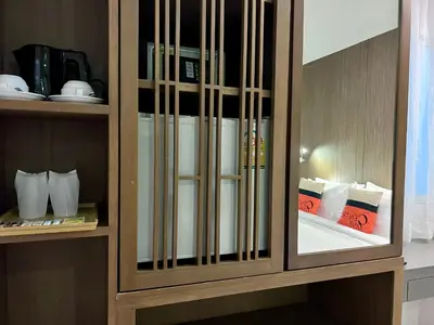 a wooden cabinet with glass doors with dishes in it at Centro One Patong in Patong Beach