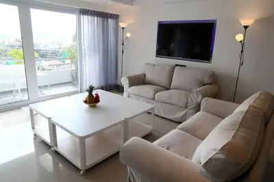 a living room with a couch and a table and a tv at Swiss Villas Panoramic - Hillside Beach View in Patong Beach