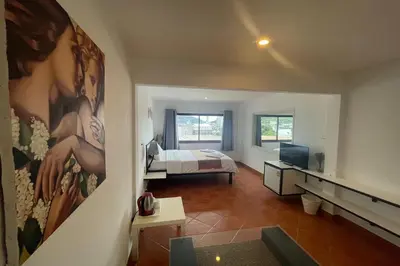 a room with a bedroom with a bed and a television at Swiss Villas Panoramic - Hillside Beach View in Patong Beach