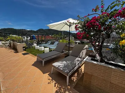 a patio with chairs and an umbrella and flowers at Swiss Villas Panoramic - Hillside Beach View in Patong Beach
