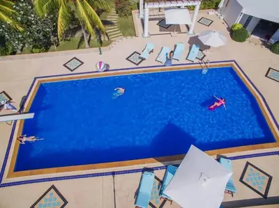 an overhead view of a large swimming pool with people in it at Villa Nirvana - Beachfront Tropical Chic 4BR Haven in Cape Panwa, Phuket in Ban Ao Makham