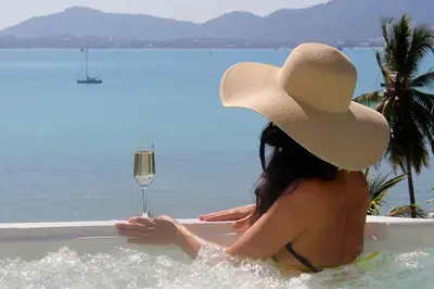 a woman sitting in a bath tub with a glass of wine at Villa Nirvana - Beachfront Tropical Chic 4BR Haven in Cape Panwa, Phuket in Ban Ao Makham