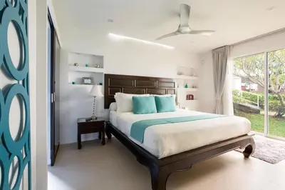 a bedroom with a large bed and a window at Villa Nirvana - Beachfront Tropical Chic 4BR Haven in Cape Panwa, Phuket in Ban Ao Makham