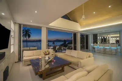 a living room with couches and a table in a room at Villa Nirvana - Beachfront Tropical Chic 4BR Haven in Cape Panwa, Phuket in Ban Ao Makham
