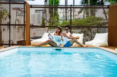 a man and woman sitting next to a swimming pool at The Tint At Phuket Town - SHA Plus in Phuket Town