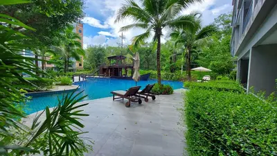 a swimming pool with two benches in front of a building at Cozy Apartment Close to Amazing Beach ! 39 Sqm in Phuket Town