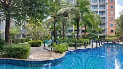a swimming pool with palm trees and a building at Cozy Apartment Close to Amazing Beach ! 39 Sqm in Phuket Town