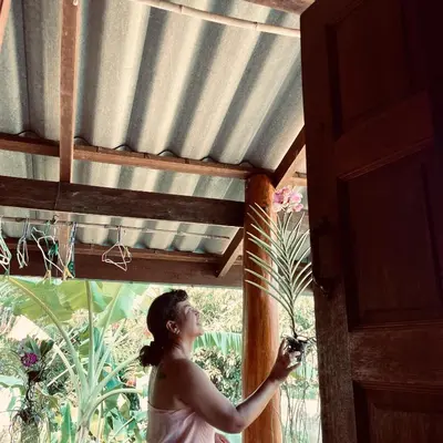 a woman standing in a doorway holding a plant at Artist Homestay in Ko Yao Noi