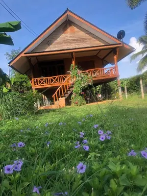 a house with a deck in a field of flowers at Artist Homestay in Ko Yao Noi