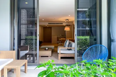 a room with a patio with chairs and tables at Baan Mai Khao - 2 Bedroom Luxury Condo - Direct Pool & Beach Access in Mai Khao Beach