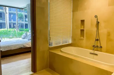 a bathroom with a tub and a bed and a window at Baan Mai Khao - 2 Bedroom Luxury Condo - Direct Pool & Beach Access in Mai Khao Beach