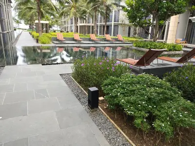 a courtyard with chairs and a pool in a building at Baan Mai Khao - 2 Bedroom Luxury Condo - Direct Pool & Beach Access in Mai Khao Beach