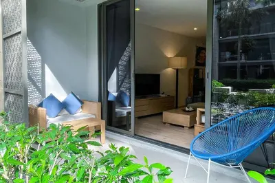 a patio with a blue chair and a television at Baan Mai Khao - 2 Bedroom Luxury Condo - Direct Pool & Beach Access in Mai Khao Beach