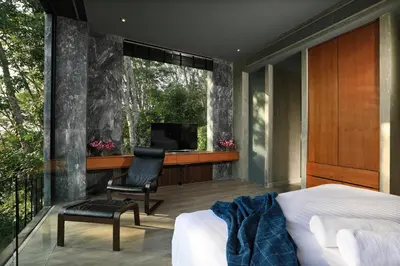 a bedroom with a bed and a chair and a television at Seclusion in the mountains, villa near Kamala beach in Kamala Beach