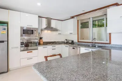 a kitchen with white cabinets and a granite counter top at Villa Mauao - Luxury Villa in Katamanda, Kata in Kata Beach