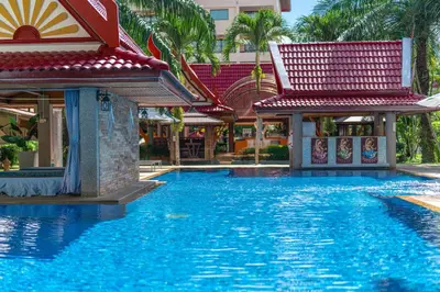 a pool at a resort with palm trees and a building at Sai Rougn apartment in Patong Beach