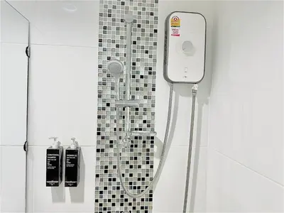 a shower in a bathroom with a black and white tiles at Ahad Suite Aonang in Ao Nang Beach