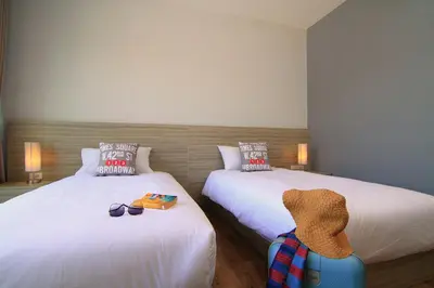 a bedroom with two beds and a suitcase on the floor at The Fusion Resort Hotel in Chalong