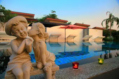 a statue of two children sitting on a bench near a pool at The Fusion Resort Hotel in Chalong
