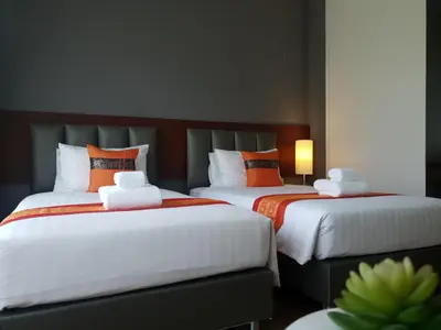 two beds with orange and white pillows in a room at The Fusion Resort Hotel in Chalong