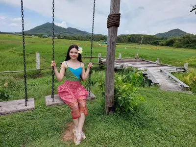 a woman sitting on a swing in a field at Rongna Villas in Ko Yao Noi