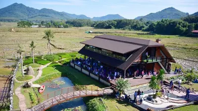 a building with people standing outside of it next to a river at Rongna Villas in Ko Yao Noi