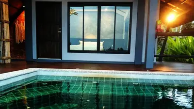 a swimming pool in front of a house with a window at Rongna Villas in Ko Yao Noi