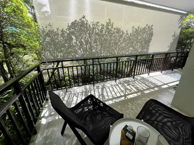 a balcony with a black chair and a window at Direct pool access 2br apartment @The Title Rawai in Rawai Beach