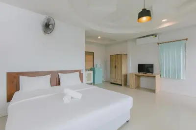 a bedroom with a white bed and a television at Kataonsea bungalows in Kata Beach