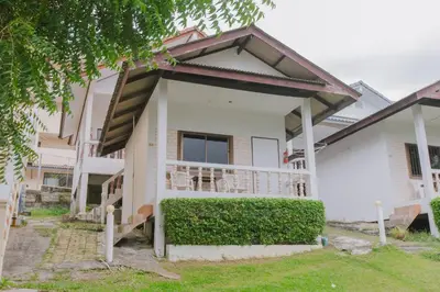 a white house with a porch and bushes at Kataonsea bungalows in Kata Beach