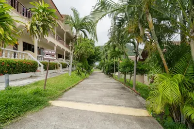 a street in front of a building with palm trees at Kataonsea bungalows in Kata Beach