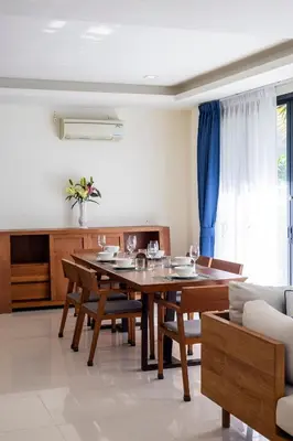 a dining room with a wooden table and chairs at Laguna Park Modern Pool Villa in Phuket Town