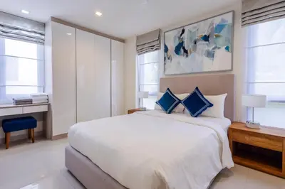 a bedroom with a large white bed with blue pillows at Laguna Park Modern Pool Villa in Phuket Town