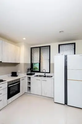 a kitchen with white cabinets and a refrigerator at Laguna Park Modern Pool Villa in Phuket Town