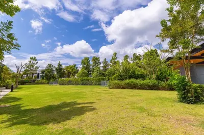 a large grassy yard with a fence and trees at Laguna Park Modern Pool Villa in Phuket Town